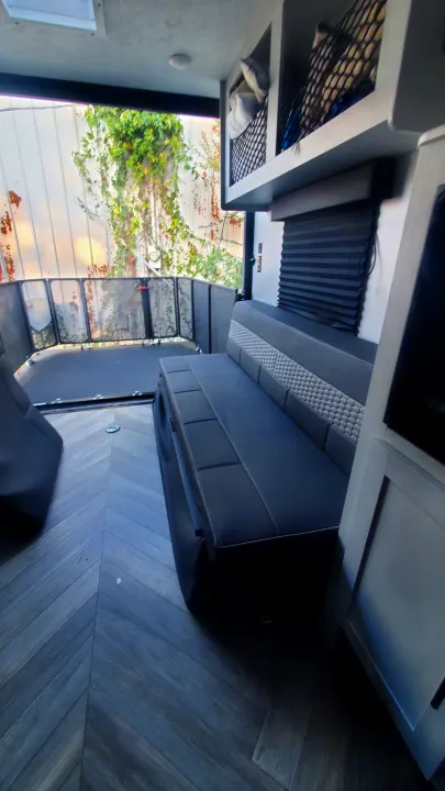 Spacious RV rental interior featuring a versatile rear patio, comfy seating, smart mesh storage, and stylish herringbone flooring.. Forest River Wildwood 2022
