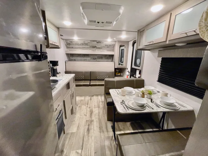 RV rental interior: modern kitchen, dining booth, and rear bed for comfortable living.. Dutchmen Coleman Lantern LT 2022