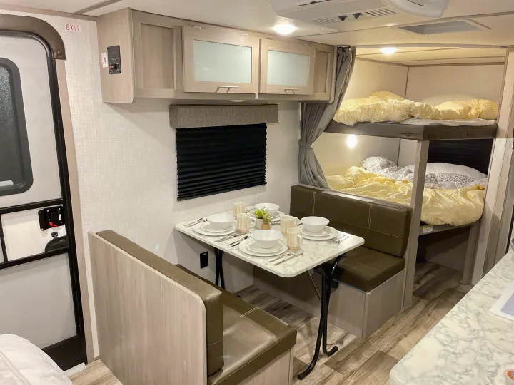 RV rental interior: cozy dinette, overhead cabinets, & comfy bunk beds. Perfect for travel adventures!. Dutchmen Coleman Lantern LT 2022