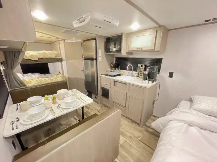 This rv rental shows a cozy interior with a dining area, kitchen, bunk beds, and a main bed, perfect for travel.. Dutchmen Coleman Lantern LT 2022