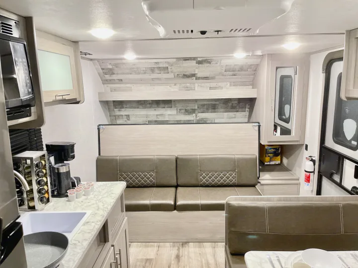 This RV rental shows a bright, modern interior with a well-equipped kitchenette (microwave, sink, coffee maker) and a comfortable dinette.. Dutchmen Coleman Lantern LT 2022