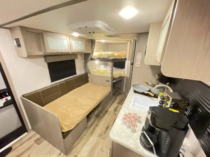 This RV rental interior features convertible dinette seating, cozy bunk beds, and a well-equipped kitchenette for your travels.. Dutchmen Coleman Lantern LT 2022