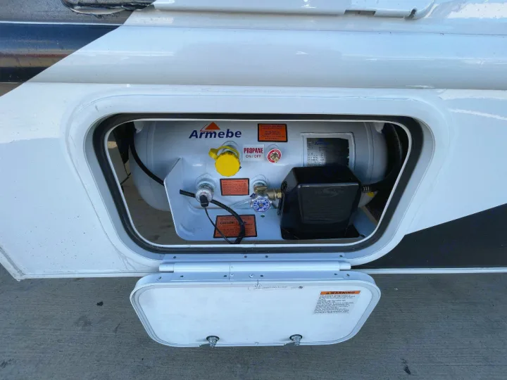 An RV rental's main propane tank is shown in its side compartment. This essential fuel source powers the recreation vehicle.. Thor Freedom Elite 2022