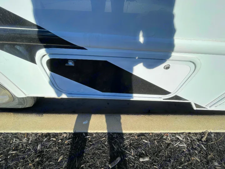 Side view of an RV rental: a white storage compartment with black diagonal stripes.. Thor Freedom Elite 2022
