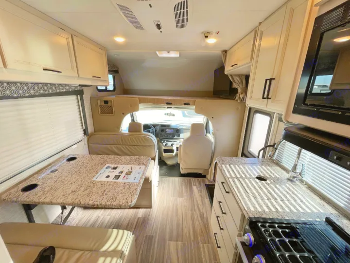 Inside an RV rental showing a kitchen, dinette with seating, and an overhead bunk above the driver's cab.. Thor Freedom Elite 2022