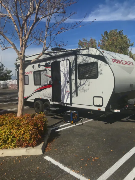 Powerlite RV rental with open door and generator in a sunny paved lot. Perfect for adventure trips.. Pacific Coachworks Powerlite 2020
