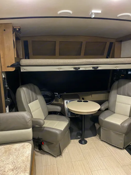 RV rental interior featuring a drop-down cab bunk bed, swiveling captain's chairs, and a small table for comfortable travel.. FR3 FR3 Motorhome 2021