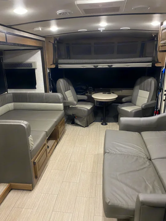 Inside a modern rv rental: ample gray seating, convertible dinette, cockpit chairs, and an overhead bunk. Ready for your adventure.. FR3 FR3 Motorhome 2021