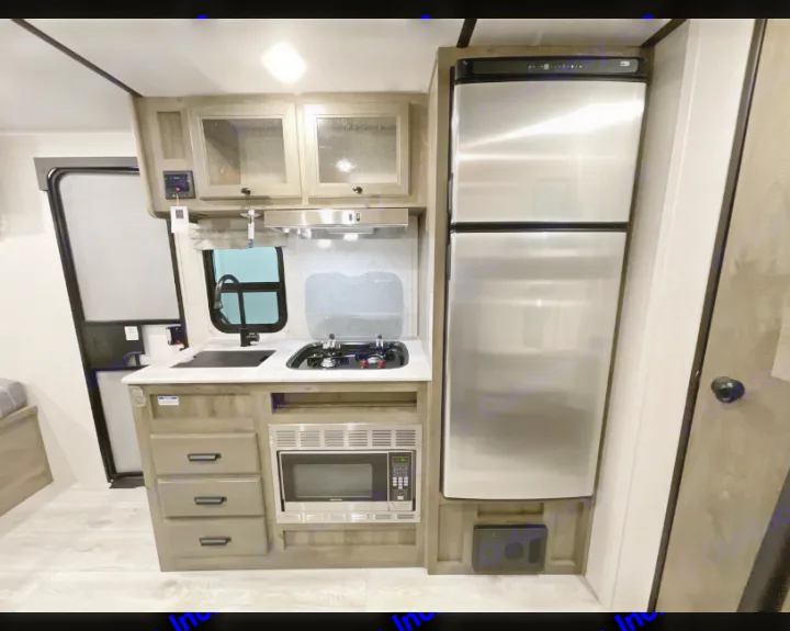 This RV rental kitchen boasts a compact design with a sink, two-burner stove, microwave, and full-size fridge.. Forest River Surveyor Legend BHLE 2022