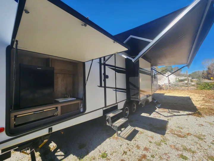 This rv rental offers an outdoor kitchen with a fridge and sink, plus an extended awning, perfect for camping.. Crossroads Sunset Trail 2021