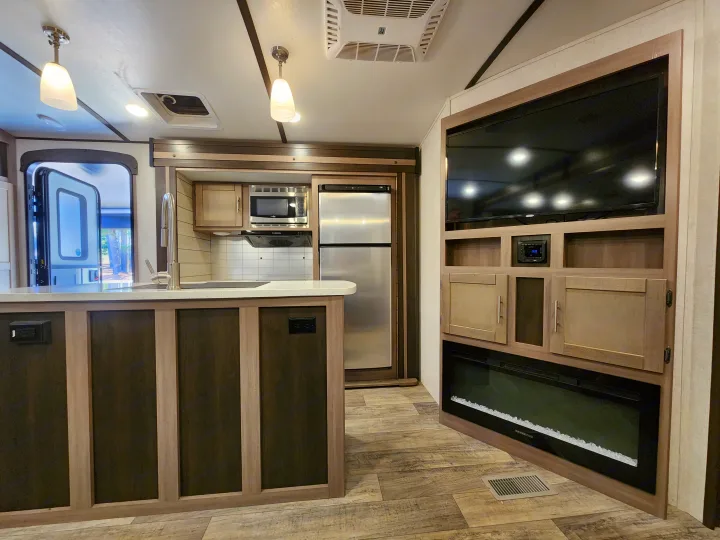 Spacious RV rental interior featuring a modern kitchen island, full kitchen, and living area with TV and fireplace.. Crossroads Sunset Trail 2021