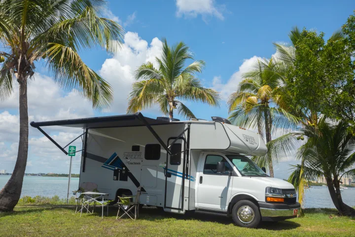 Enjoy this Class C rv rental at a scenic waterfront campsite with palm trees under a sunny blue sky.. Forest River Coachmen Cross Trail XL 2022
