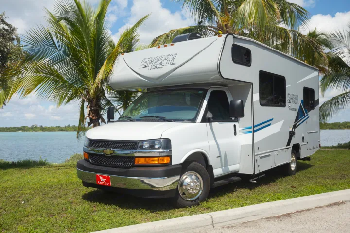 Enjoy a scenic RV rental adventure! This white Coachmen motorhome is parked by clear water & palm trees, perfect for travel.. Forest River Coachmen Cross Trail XL 2022