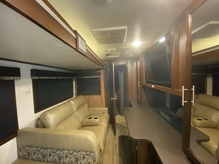 View inside an RV rental showing a light-colored couch, entertainment area with TV, and modern decor.. Jayco White Hawk 2019