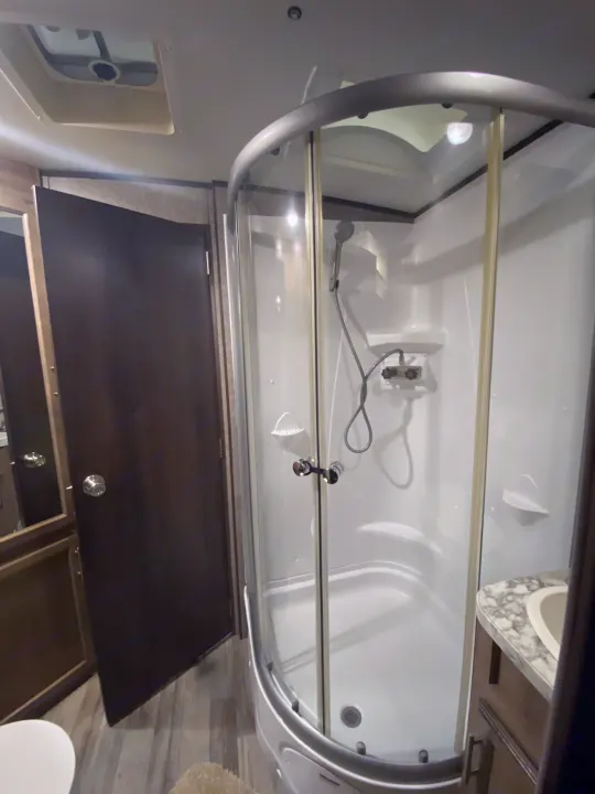 Compact shower and bathroom area in an RV rental, featuring a glass enclosure and basic fixtures.. Jayco White Hawk 2019