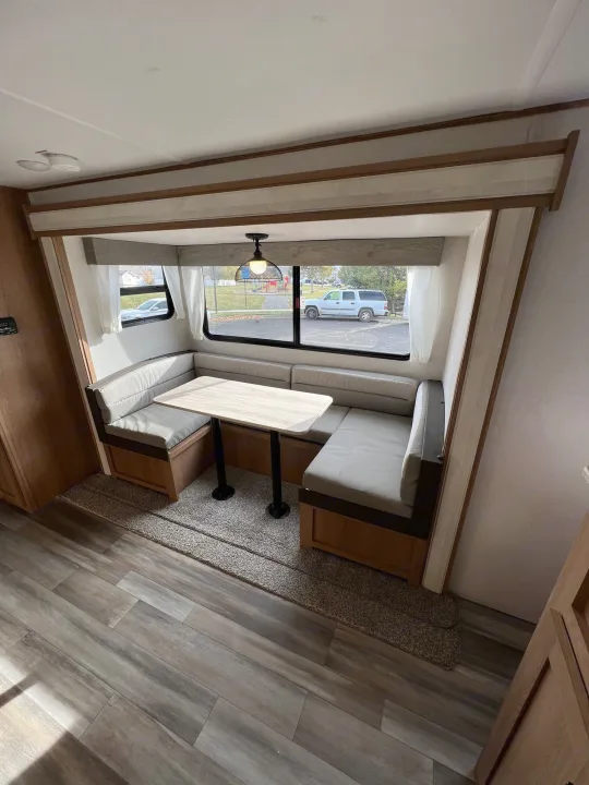 Cozy RV rental dinette with comfortable seating and large windows. Perfect for meals and enjoying the views.. Prime Time Avenger 2022
