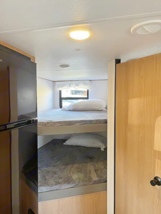 Inside an RV rental: two comfortable bunk beds, a refrigerator, and a bright, well-lit interior. Ideal for family trips.. Prime Time Avenger 2022