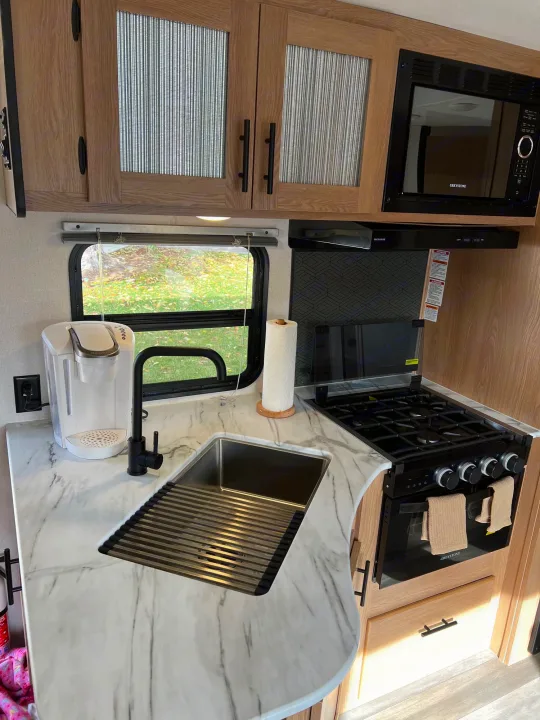 RV rental: Modern kitchen with marble-look counter, stainless sink, black faucet, coffee maker, microwave, and gas stove.. Prime Time Avenger 2022