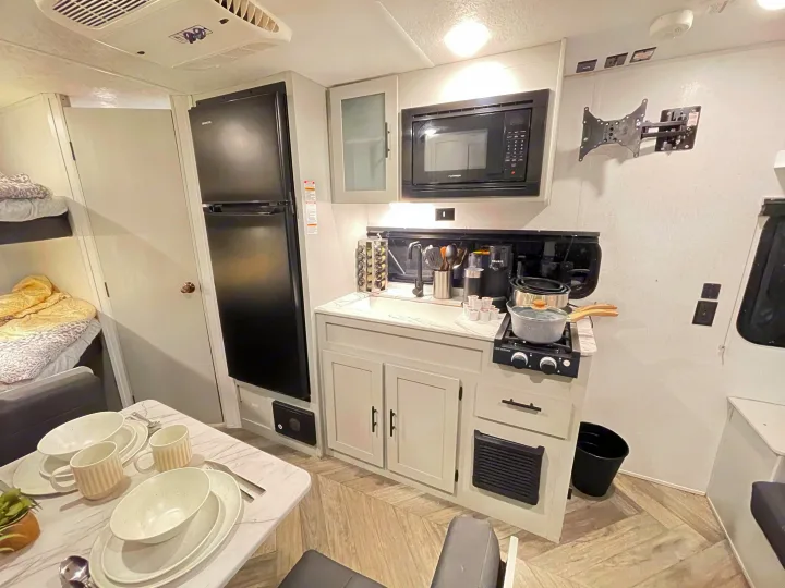 This RV rental offers a modern, compact kitchen with a microwave, sink, stovetop, and a cozy dinette.. Forest River Salem FSX 2021