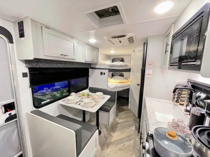 Modern RV rental interior: cozy kitchen, dining booth, and bunk beds. Perfect for family adventures.. Forest River Salem FSX 2021
