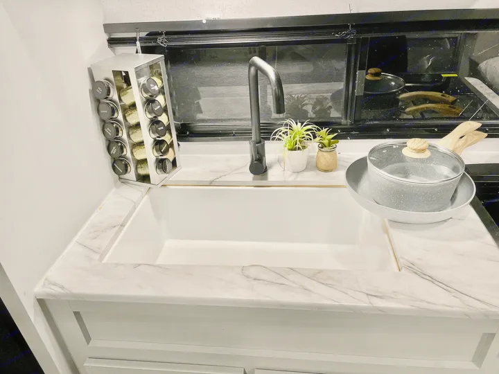 Modern RV rental kitchen with sink, black faucet, marble countertop, spice rack, and cooking essentials.. Forest River Salem FSX 2021