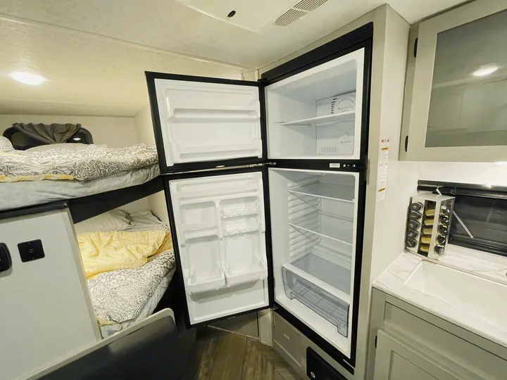 This rv rental features an open refrigerator, compact kitchen sink, and cozy bunk beds. Ideal for camping adventures.. Forest River Salem FSX 2021