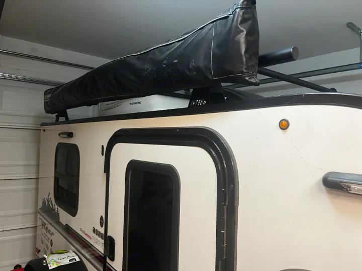 White Intech Flyer travel trailer, ideal for rv rental adventures, parked indoors with rooftop awning & AC unit.. Custom Camper 2021