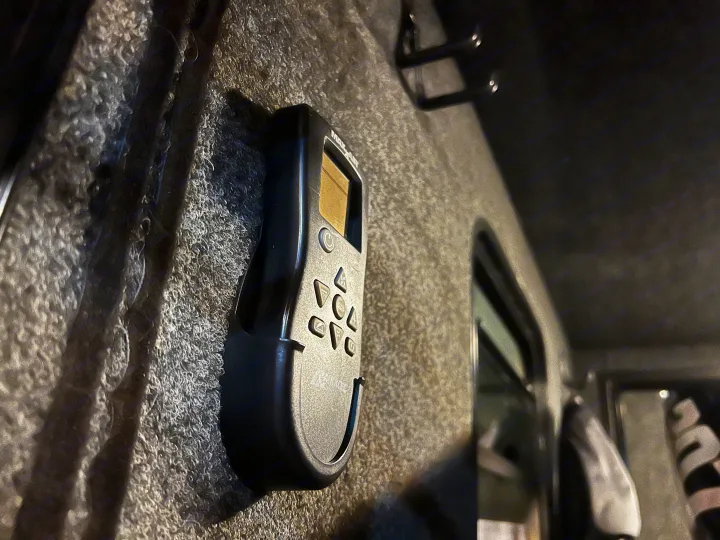 Maxxair fan remote, mounted on a textured wall inside an RV rental. Control your comfort effortlessly.. Custom Camper 2021