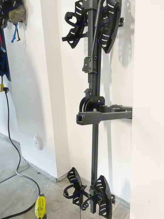 Black hitch-mount bike rack, perfect for an RV rental adventure. Stored upright indoors, ready for use.. Custom Camper 2021
