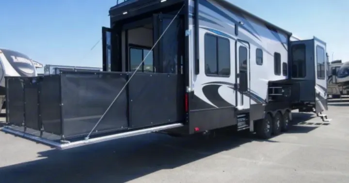 Toy hauler RV rental with deployed rear patio deck and mesh railings, ideal for adventurers seeking spacious travel trailer comfort.. Heartland Cyclone 2018