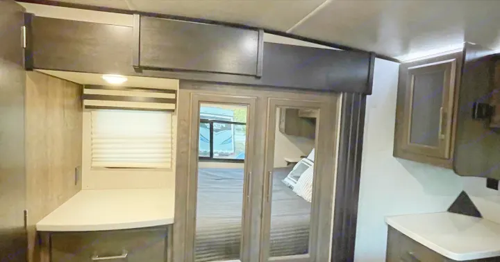 Modern RV rental interior: dark wood cabinetry, light counter, window, and mirrored bedroom doors for a spacious feel.. Heartland Cyclone 2018