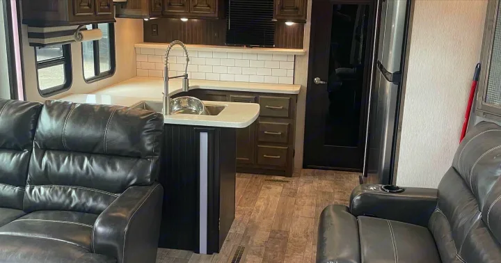 Spacious RV rental interior with a modern kitchen, comfortable leather seating, and wood-look flooring.. Heartland Cyclone 2018