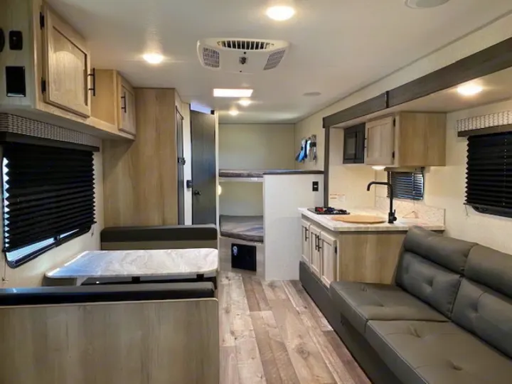 Spacious RV rental interior with a modern kitchen, dinette, and bunk beds, offering a comfortable travel trailer experience.. Escape e231bh 2022