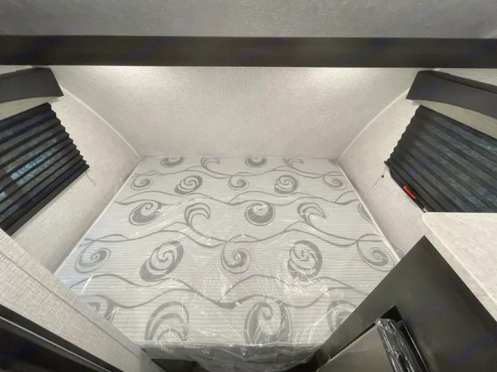 Inside an RV rental: a clean, new mattress in its plastic wrap in a cozy sleeping alcove with side windows.. Braxton Creek BUSHWHACKER PLUS 17FD 2022