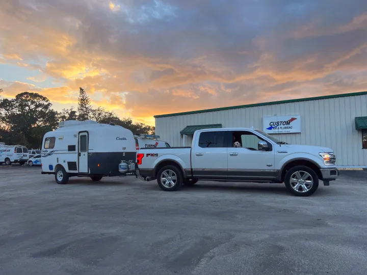 A white pickup truck with a dog tows an RV rental at sunset. Parked at a business, ready for a road trip adventure!. Casita 17' Spirit Deluxe 2010