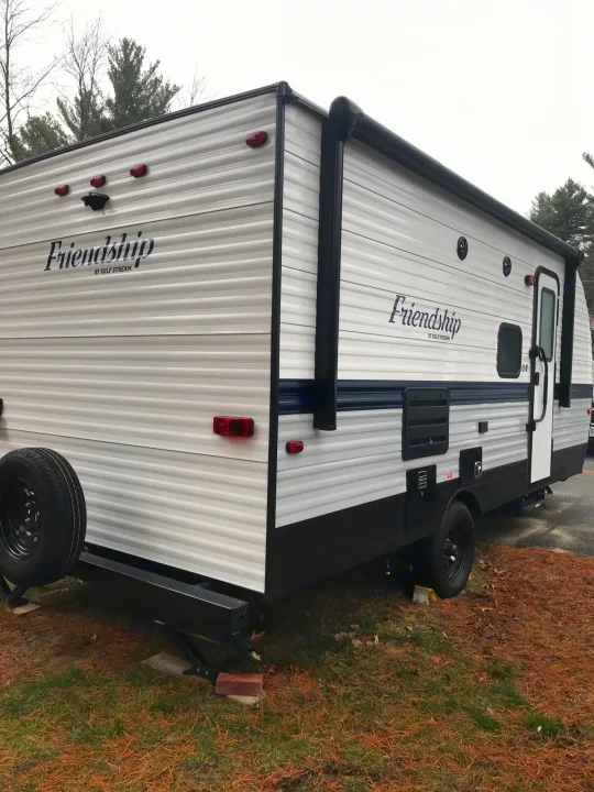 White "Friendship" travel trailer for RV rental, parked outdoors. Features rear camera, awning, and stabilizer jacks.. Gulf Stream Friendship 2022