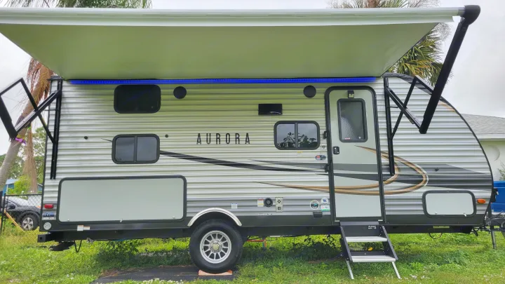 This sleek Aurora travel trailer, ready for your next RV rental adventure, features a large extended awning with cool blue LED lights.. Forest River Coachmen Aurora 2022