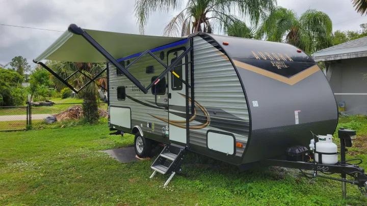 Discover this spacious gray & black travel trailer RV for rent, featuring an extended awning, ready for your next adventure.. Forest River Coachmen Aurora 2022
