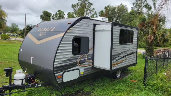 Gray Aurora Forest River travel trailer RV rental with slide-out extended, parked on grass, ready for camping.. Forest River Coachmen Aurora 2022