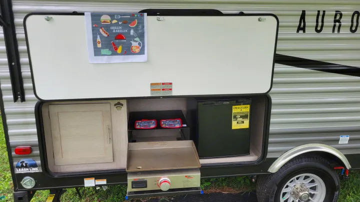 This rv rental offers an outdoor kitchen with a griddle, mini-fridge, and cabinet storage for convenient camping meals.. Forest River Coachmen Aurora 2022