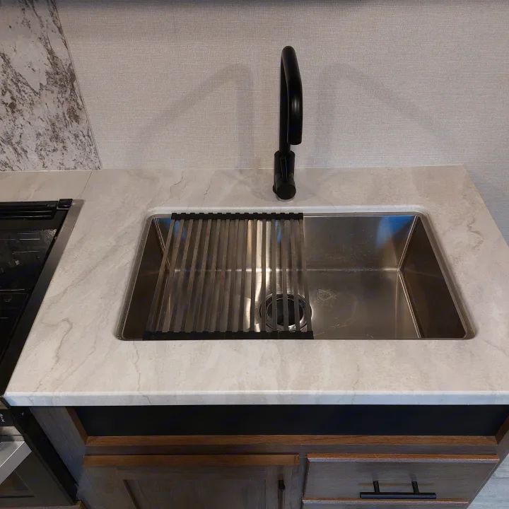 RV rental kitchen: stainless steel sink with drying rack, light countertop, and modern wood cabinets.. Avenger Avenger Trailer 2021