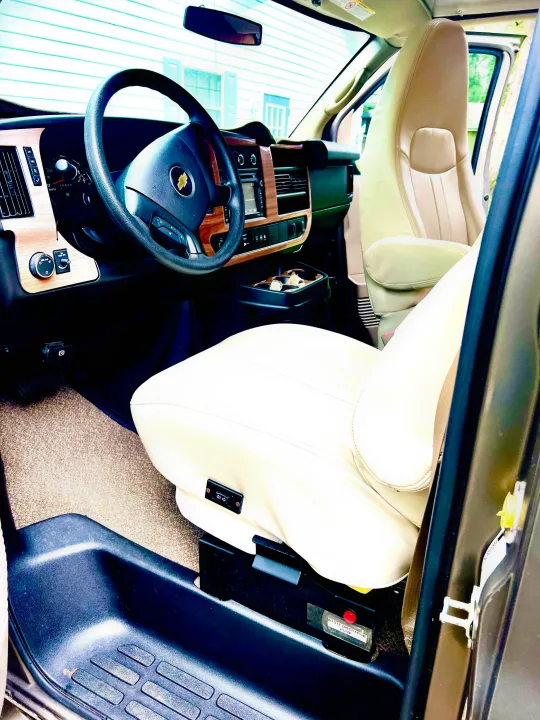 Explore this RV rental's luxurious front cabin: wood-grain dashboard, comfortable beige seats, and essential waste discharge pump.. Roadtrek Roadtrek Class B 2015