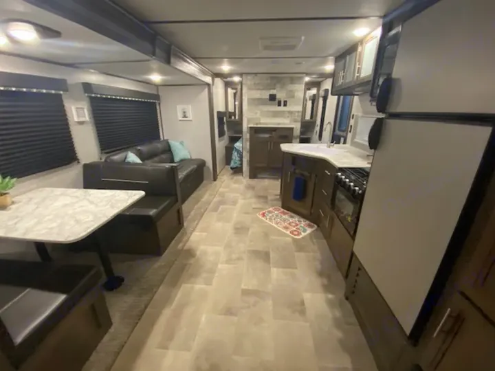 Spacious RV rental interior featuring a modern kitchen, living area with sofa and table, and versatile cargo bay.. Keystone RV CMMM262BH21 2021