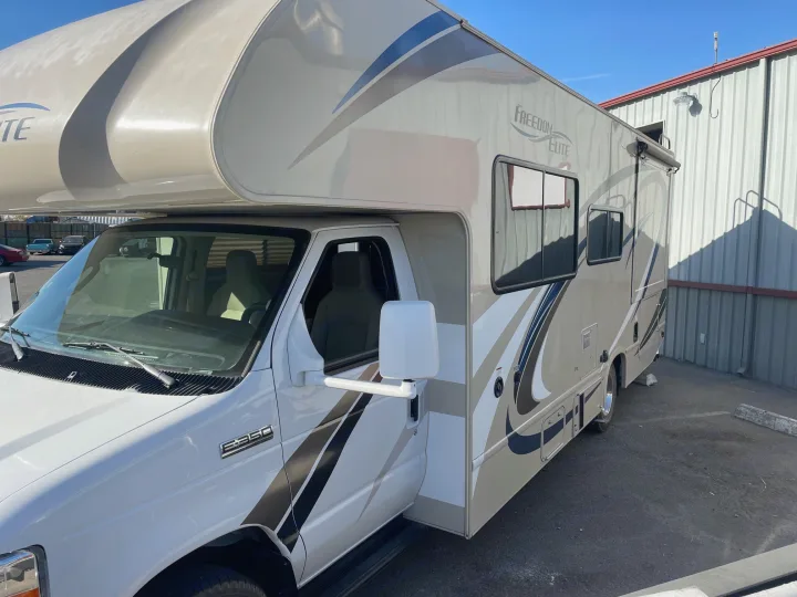 A white and tan Freedom Elite Class C RV rental, with a Ford E-350 front, parked outdoors. Ready for adventure!. Thor Motor Coach Freedom Elite 2019
