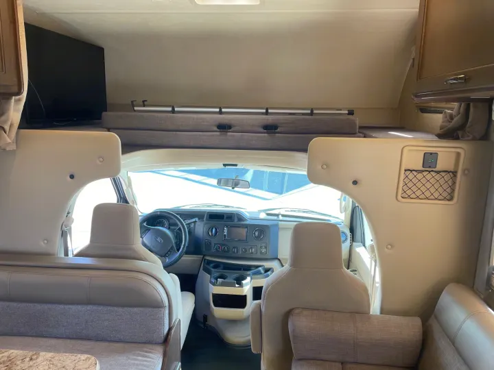 Spacious RV rental interior showing driver's cabin, overhead bunk with TV, and comfortable seating areas.. Thor Motor Coach Freedom Elite 2019