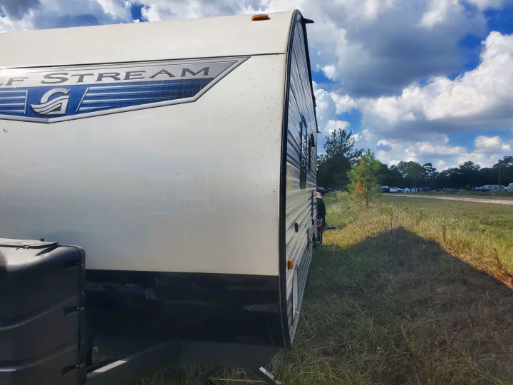 A white Gulf Stream RV, available for rv rental, is parked in a grassy field with other campers under a cloudy sky.. Gulf Stream Kingsport 2022