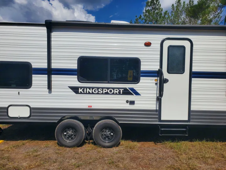 Detailed side view of a white Kingsport travel trailer, perfect for your next RV rental. Features include windows and an entry door.. Gulf Stream Kingsport 2022
