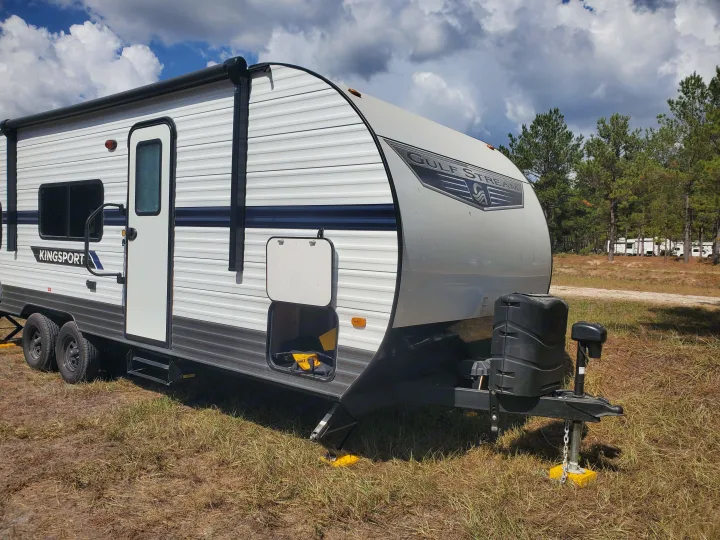 A Kingsport travel trailer (Gulf Stream) set up at a scenic campground. Perfect for your next RV rental adventure!. Gulf Stream Kingsport 2022