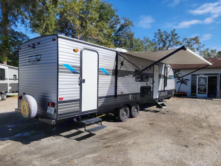 Spacious gray travel trailer RV rental with extended awning, parked on gravel at a dealership, ready for adventure.. Forest River Salem Cruise Lite 2020