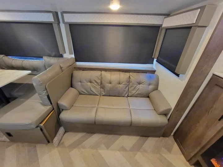 Modern RV rental interior: cozy light grey sofa, versatile dinette, and dark blinds. A comfortable space for your journey.. Forest River Salem Cruise Lite 2020